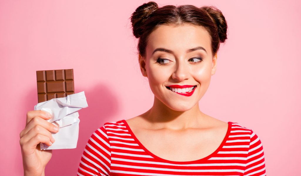 Close-up portrait of nice cute charming attractive winsome glamorous cheerful girl wearing striped t-shirt holding in hands looking favorite dessert life lifestyle advert isolated on pink background.